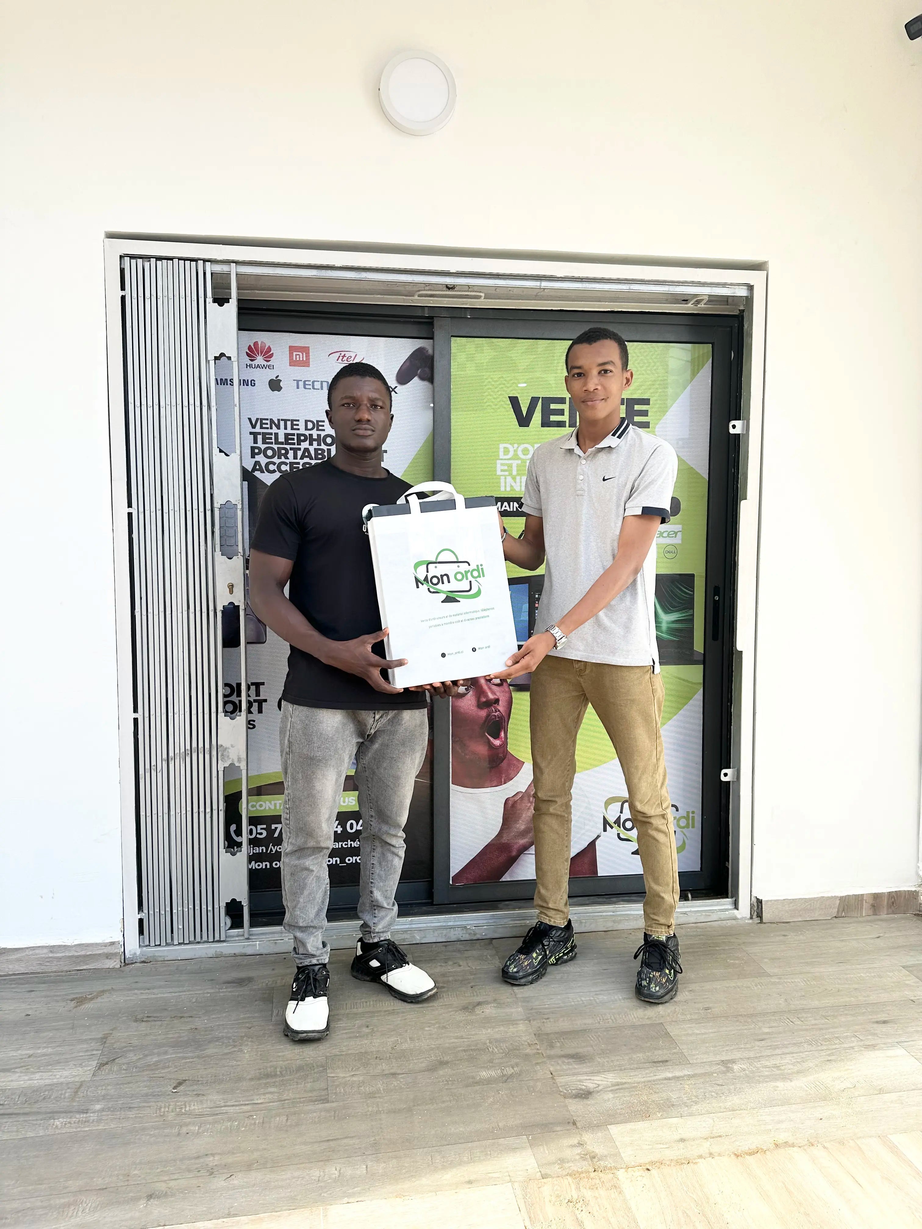 Christopher DE PASQUAL et un client satisfait à l'entré de la boutique sis à Yopougon